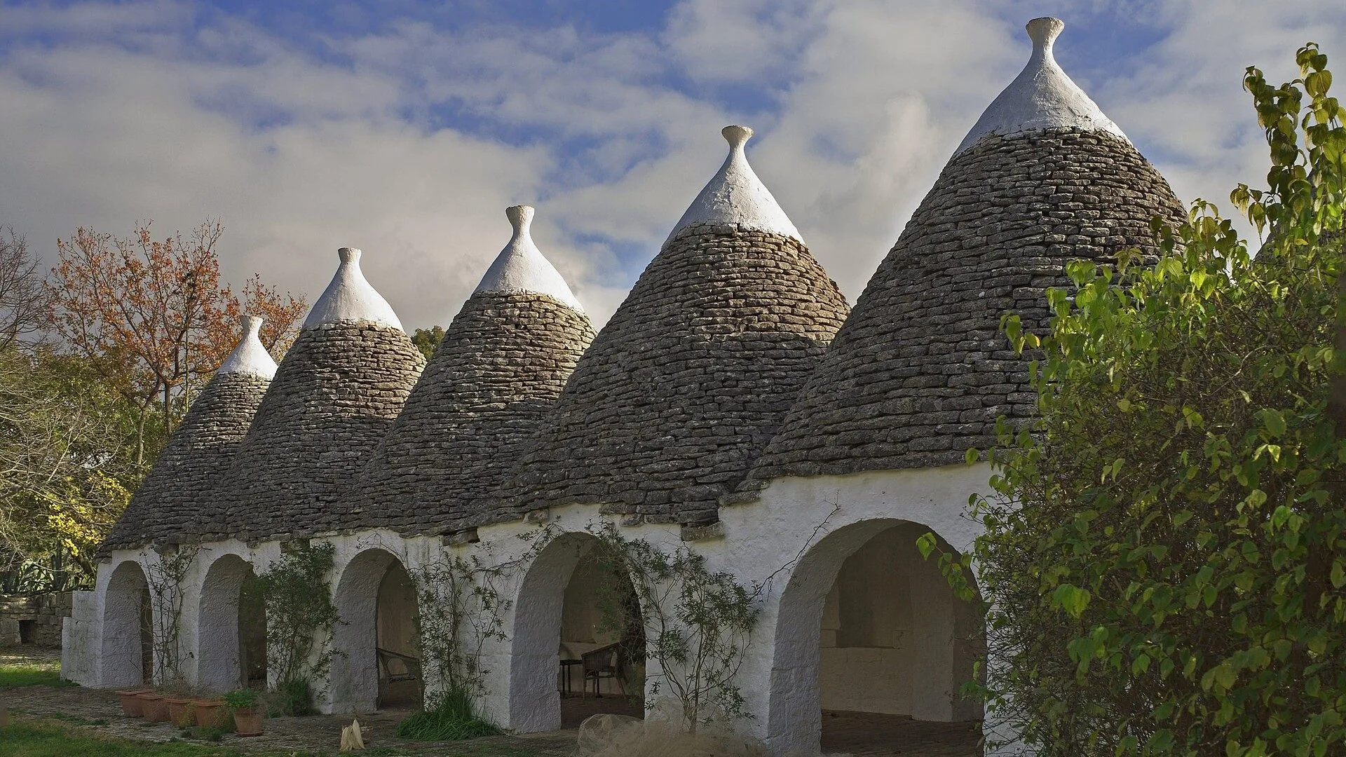 Una fila di trulli con i tetti conici in pietra e i portici ad arco